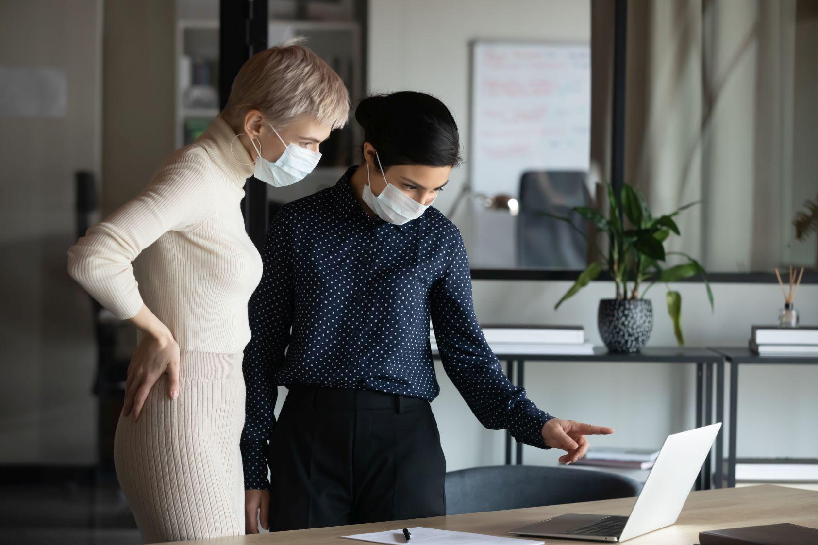 Zwei Frauen stehen gemeinsam an einem Tisch mit Laptop